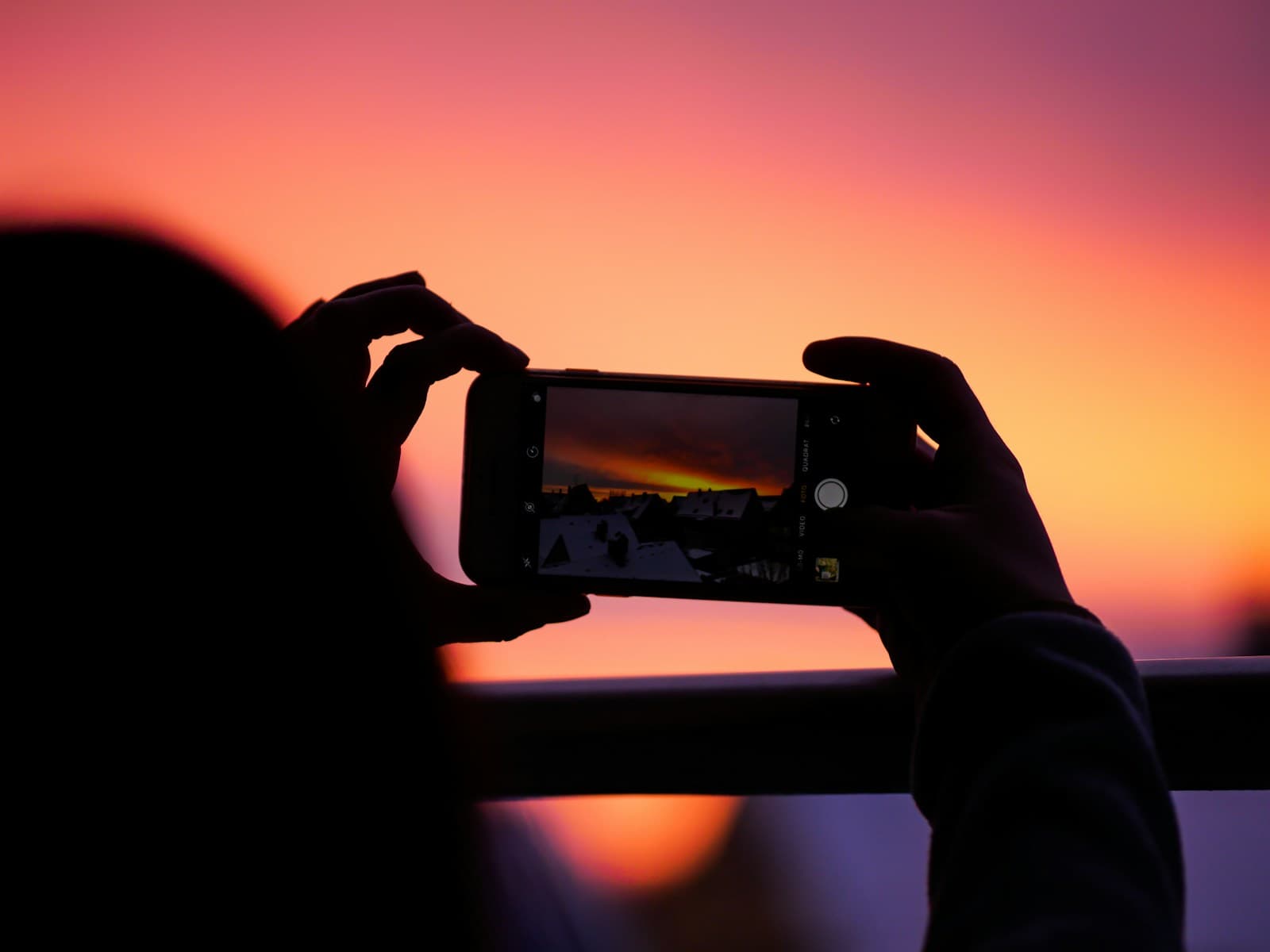 Tourist capturing a sunset photo on a smartphone